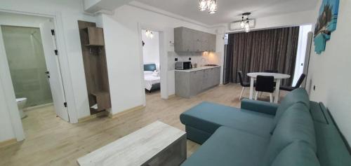 Il comprend un salon avec un canapé bleu et une cuisine. dans l'établissement Infinity Aparthotel & Spa Resort Prima Linie la Mare, Piscina Infinity la Etaj 11 Panorama, à Mamaia Nord – Năvodari