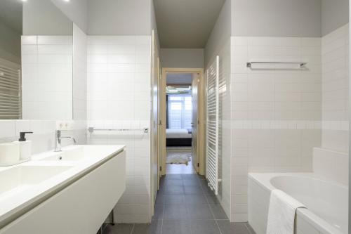 ブリュッセルにあるBeautiful 1 bedroom apartment close to Parc de Bruxellesの白いバスルーム(シンク2台、バスタブ付)