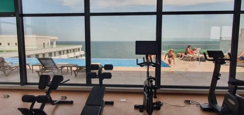 una palestra con vista sulla piscina e sulle persone di Infinity Aparthotel & Spa Resort Prima Linie la Mare, Piscina Infinity la Etaj 11 Panorama a Mamaia Nord - Năvodari