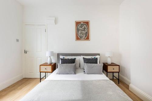 a white bedroom with a large bed with two night stands at Stylish one bedroom apartment in Greater London in London