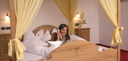 a woman laying in a bed with pillows at Hotel Tonnerhof in Racines