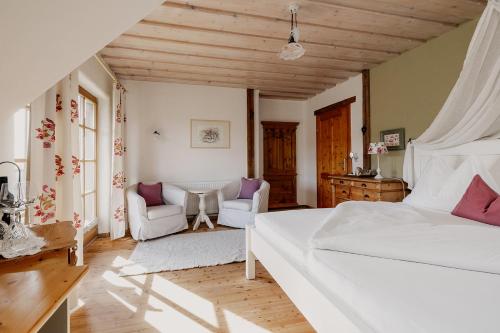 a bedroom with a white bed and two chairs at Weinhof Narat-Zitz in Leutschach