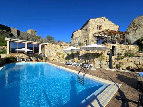 una piscina con sombrillas junto a un edificio en Casa do Penedo Castle House en Linhares