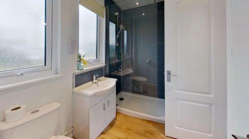 La salle de bains blanche est pourvue d'un lavabo et d'une douche. dans l'établissement 66 Trevithick Court, Tolroy Manor, à Hayle
