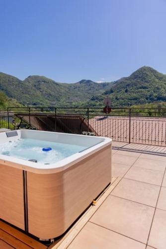 a hot tub on a balcony with mountains in the background at La Terrazza sui Monti in Castiglione dʼIntelvi