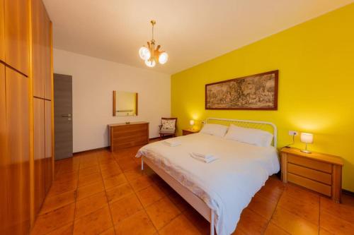a bedroom with a white bed and a yellow wall at La Terrazza sui Monti in Castiglione dʼIntelvi