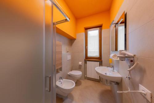 a bathroom with two sinks and a toilet and a window at La Terrazza sui Monti in Castiglione dʼIntelvi