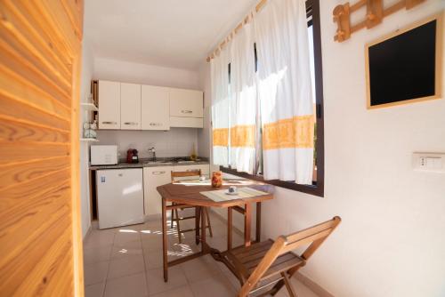 a small kitchen with a wooden table and chairs at Monolocale Free Beach Residence due passi dal mare in Costa Rei
