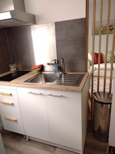 cocina blanca con fregadero y fogones en Studio indépendant location courte durée à proximité de Lycée International en Saint-Germain-en-Laye