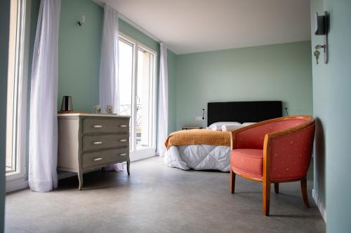 - une chambre avec un lit, une chaise et une commode dans l'établissement L'Atelier Sur Seine, à Épinay-sur-Seine