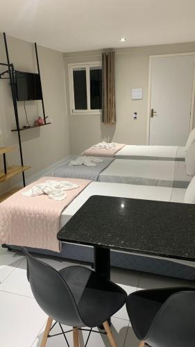two beds in a room with a table and chairs at BOB Suítes in Porto De Galinhas