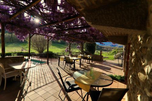 a patio with tables and chairs and purple flowers at Mas Lo Faix in Saint-Laurent-de-Cerdans