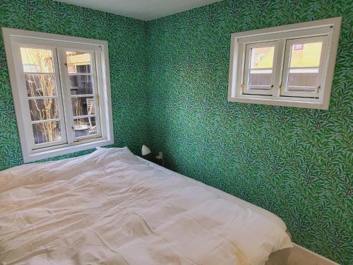 um quarto com paredes verdes e uma cama com 2 janelas em Tinghus Flat em Skagen