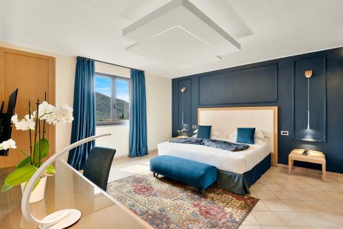 Schlafzimmer mit einem Bett mit blauen Wänden und einem Tisch in der Unterkunft Park Hotel Argento in Levanto