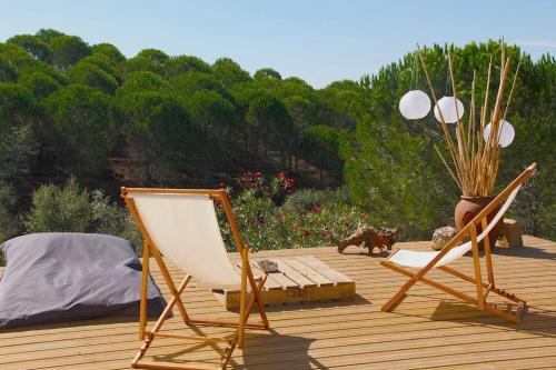 two chairs and a bed on a wooden deck at Beautiful country home immersed in nature in São Teotónio