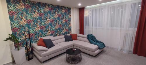 sala de estar con sofá blanco y pared colorida en Apartman Sunset, en Osijek