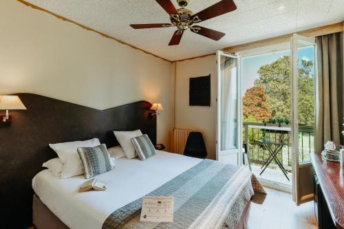 a bedroom with a bed with a ceiling fan and a window at Hôtel L'Iroko The Originals City in Aix-les-Bains