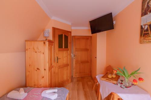 a small room with a bed and a tv on the wall at Willa Piękne Widoki in Ząb