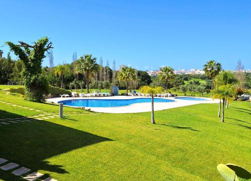 een zwembad in een park met groen gras en bomen bij Sul House in Albufeira