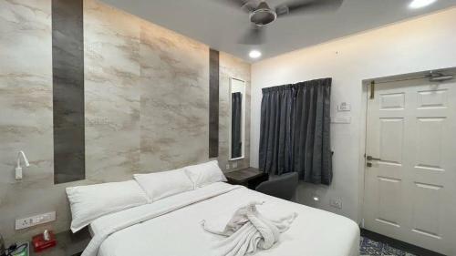 una camera da letto con un grande letto bianco con lenzuola bianche di Mayilveedu Guest House a Tuticorin