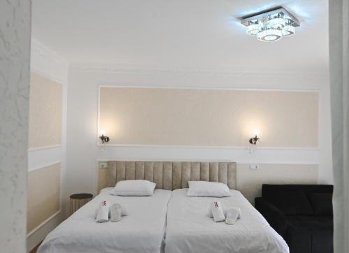 Un dormitorio con una cama con sábanas blancas y una lámpara de araña. en JERUSALEM merkaz Hotel Kutaisi en Kutaisi