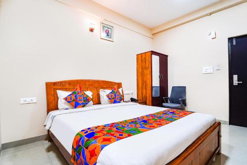 um quarto com uma cama grande e um edredão colorido em FabExpress UV Residency em Irugūr