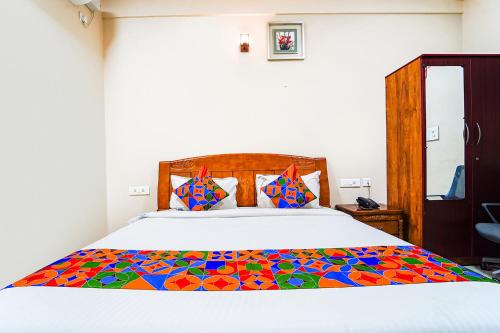 1 dormitorio con 1 cama grande y edredón colorido en FabExpress UV Residency, en Irugūr