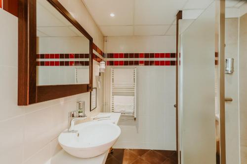 La salle de bains est pourvue d'un lavabo blanc et d'une douche. dans l'établissement Hôtel L'Iroko The Originals City, à Aix-les-Bains