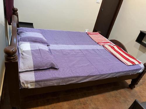 una cama con un edredón púrpura encima en Panchatattva Homestay, en Belmannu