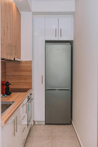 a stainless steel refrigerator in a kitchen with white cabinets at Comfy Apartment Near Acropolis in Athens