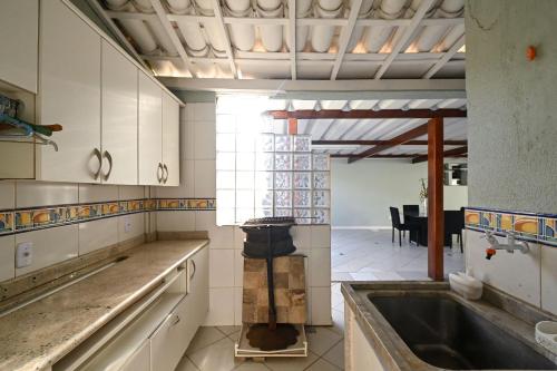 uma cozinha com um lavatório e uma sala de jantar em Casa Espaçosa com Jacuzzi e Churrasqueira RAU409 em Goiânia
