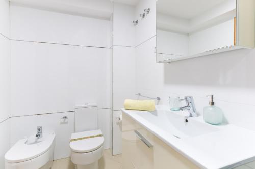 een witte badkamer met een toilet en een wastafel bij Balcón de la Catedral in Málaga
