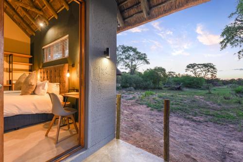 um quarto com uma cama, uma secretária e uma janela em Mziki Safari Lodge em Vaaldam