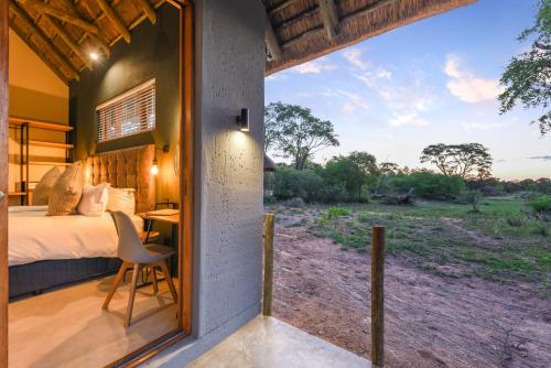 a room with a bed and a desk and a window at Mziki Safari Lodge in Vaalkop Dam