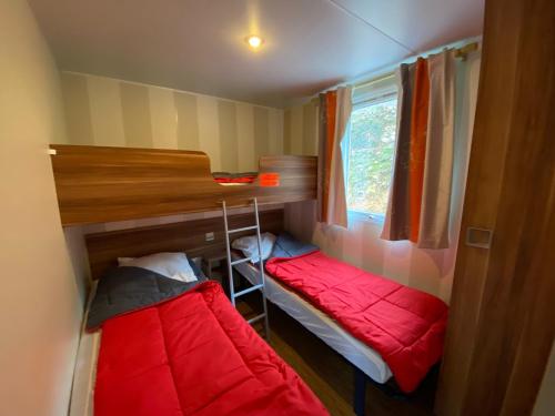 une chambre avec deux lits superposés et une fenêtre dans l'établissement Camping Cascade Aveyron, à Saint-Rome-de-Tarn
