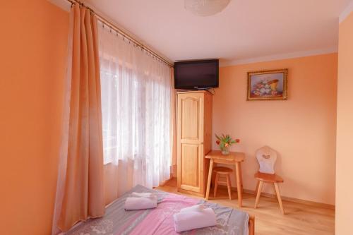 a bedroom with a bed and a tv on the wall at Willa Piękne Widoki in Ząb
