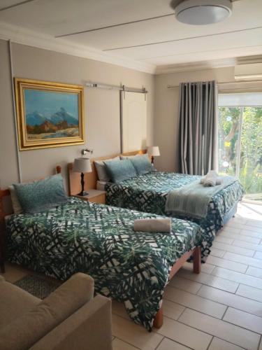 a hotel room with two beds and a couch at B@home in Bloemfontein