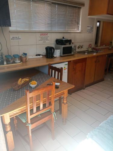 a kitchen with a wooden table and a table and chairs at B@home in Bloemfontein