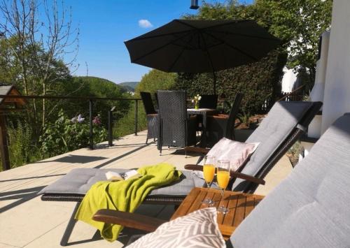 Un patio con una sombrilla y una mesa y sillas. en diemelseeholiday Ferienwohnung am Diemelsee mit Balkon, en Diemelsee