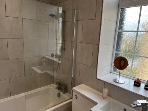 y baño con ducha, bañera y lavamanos. en Steeple View - A two bedroom 18th century cottage. en Leeds