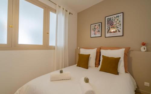 - une chambre avec un lit blanc avec des oreillers et une fenêtre dans l'établissement Chez So à 2 minutes du Vieux-Port by Weekome, à Marseille