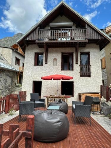 een huis met een terras met stoelen en een parasol bij Chalet Pitu in Vénosc