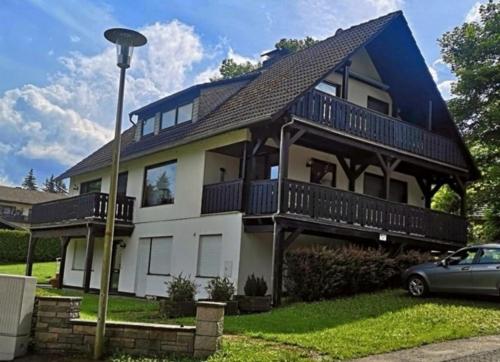 une grande maison blanche avec un toit en gambrel dans l'établissement Top Ferienwohnung am Diemelsee Sauerland, à Diemelsee