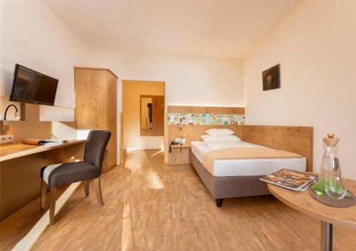 ザルツブルクにあるホテル ヘフターホフのベッド、デスク、テーブルが備わる客室です。
