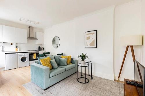 uma sala de estar com um sofá azul e uma cozinha em Stylish one bedroom apartment in Greater London em Londres