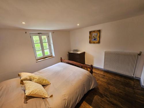 a bedroom with a bed and a window and a radiator at La villa aux volets bleus in Saint-Étienne-de-Fursac