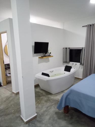 uma banheira branca num quarto com uma televisão em Chales Paraíso STL em São Thomé das Letras