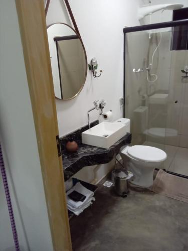 W łazience znajduje się umywalka, toaleta i lustro. w obiekcie Chales Paraíso STL w mieście São Thomé das Letras
