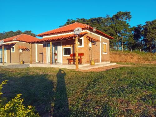 osoba stojąca przed małym domem w obiekcie Chales Paraíso STL w mieście São Thomé das Letras