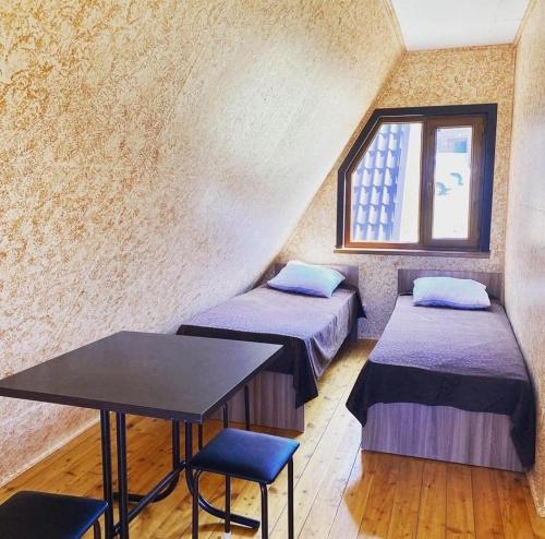 Cette chambre comprend 2 lits, une table et une fenêtre. dans l'établissement Яхта, à Zhanalyk